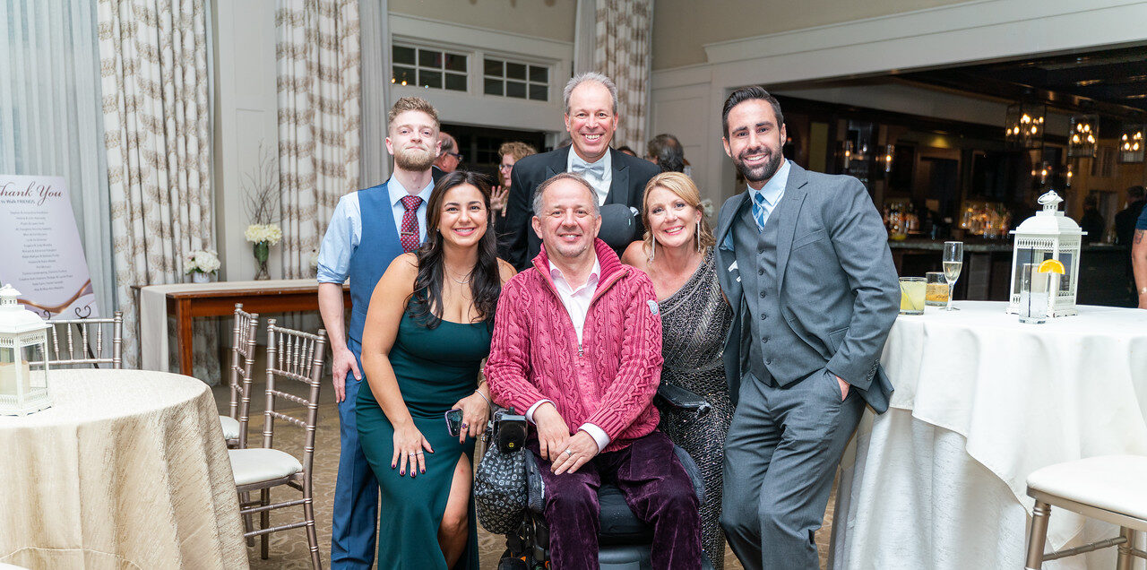 The Push to Walk team smiles for a photo with a client at the organization's 15th anniversary gala event.