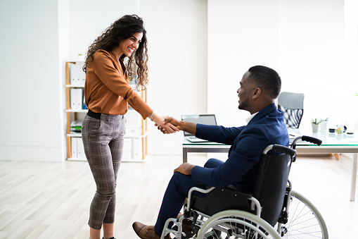Two Happy Businesspeople In Office Shaking Hands